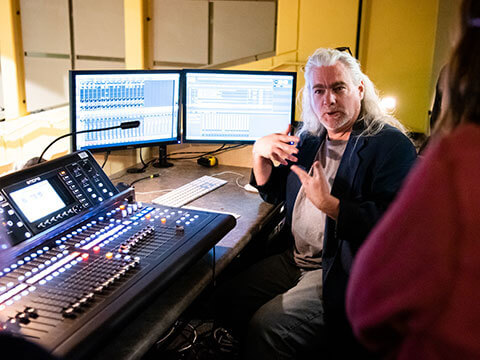 Professor instructs students on how to use a sound mixer.